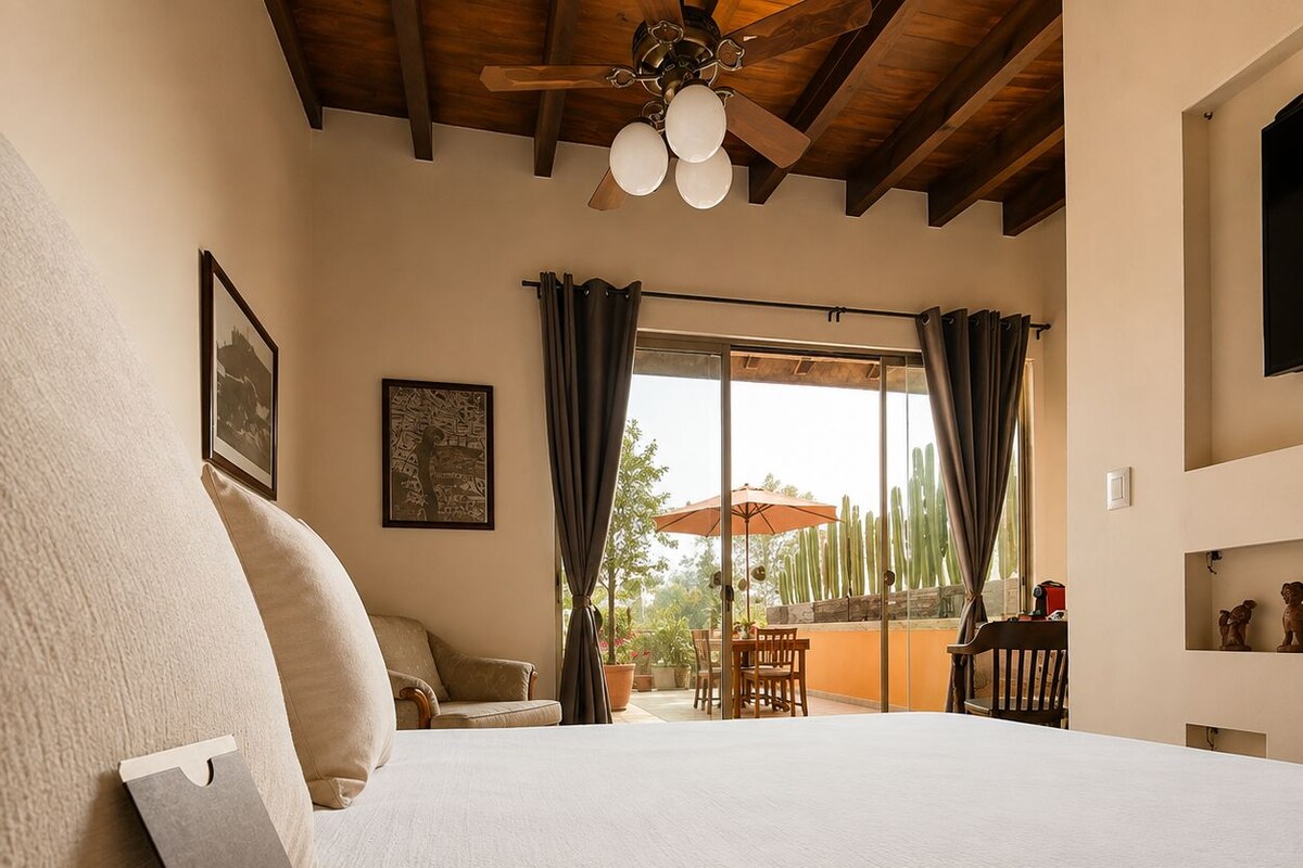 Une chambre avec un grand lit, un ventilateur de plafond, une fenêtre avec des rideaux et une vue sur l’extérieur.