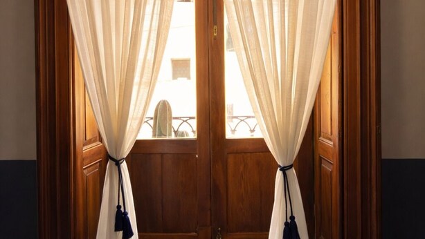 A room with wooden paneled walls, a wooden door, and a window with sheer curtains. - Hacienda Gobernadores – Boutique Stay in a Historic 19th-Century Hacienda (Mexico City)