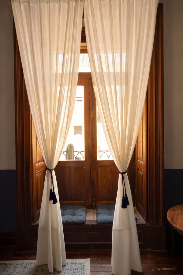 Una habitación con paneles de madera, una puerta de madera y una ventana con cortinas de tela ligera.