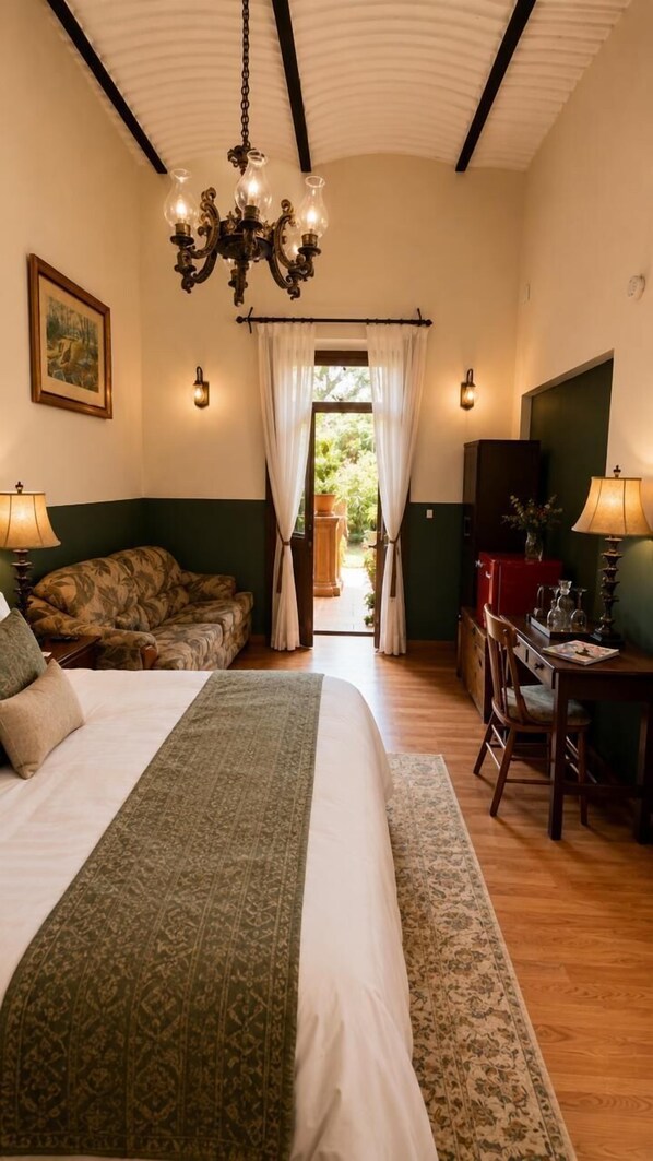 Ein Schlafzimmer mit Bett, Schreibtisch, Stuhl, einer Kronleuchter und Blick ins Freie.