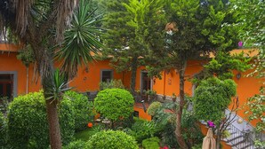 Een oranje gebouw met een binnentuin, omgeven door weelderige begroeiing en een palmboom.