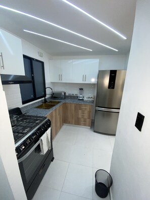 A modern kitchen with white cabinets, stainless steel appliances, and a granite countertop. - Luxurious and modern apartment 10 minutes from the aero port  (Santo Domingo Este)