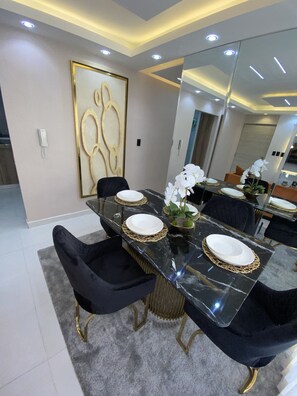 A modern dining area with a glass table, black chairs, and white plates. - Luxurious and modern apartment 10 minutes from the aero port  (Santo Domingo Este)