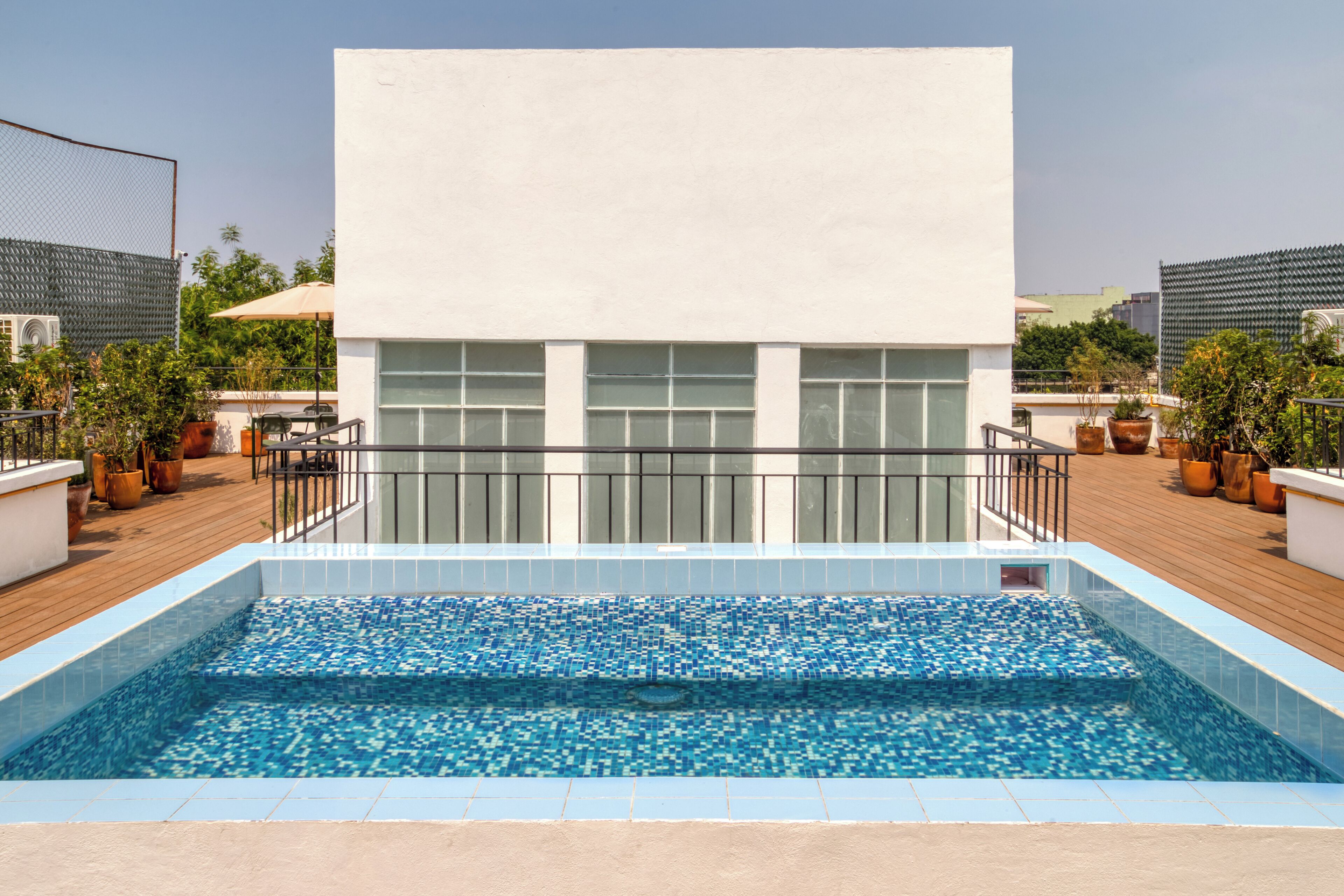 Ein Pool auf dem Dach mit einem modernen Gebäude im Hintergrund.