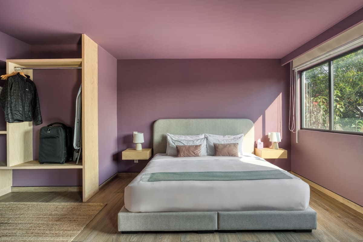 Ein Schlafzimmer mit einem Bett, Nachttischen, einem Kleiderschrank und einem Fenster.