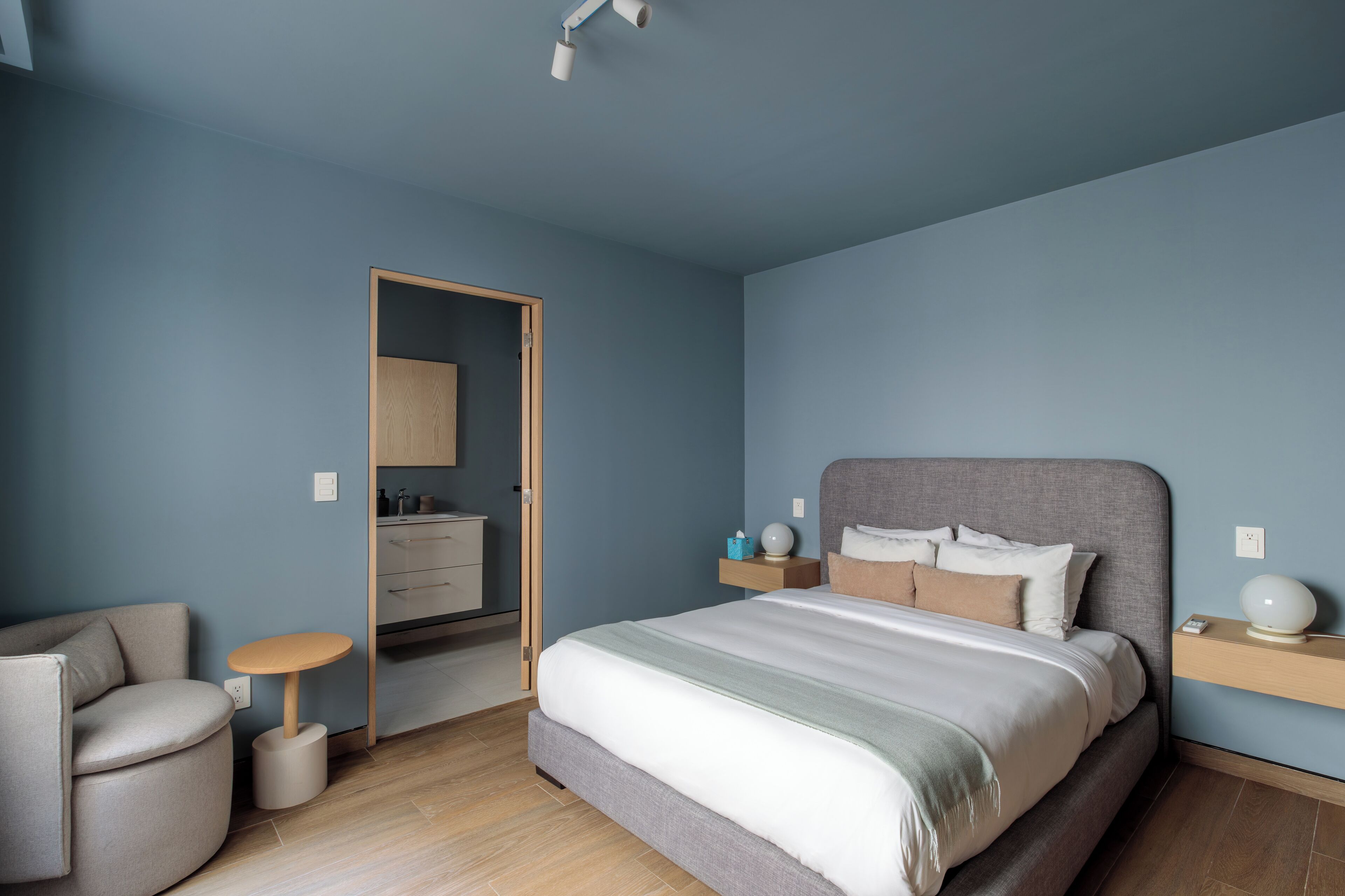 A bedroom with a bed, bedside table, chair, and a wardrobe.