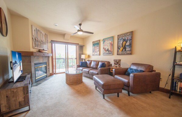 A living room with a fireplace, leather sofas, a television, and a bookshelf. - Oro Grande 308 (Keystone)