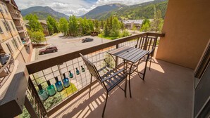 A balcony with a table and chairs, overlooking a parking area and a mountainous landscape. - Oro Grande 308 (Keystone)