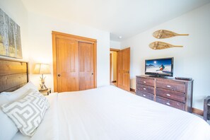 A bedroom with a large bed, wooden wardrobe, television, and wall decor. - Oro Grande 308 (Keystone)