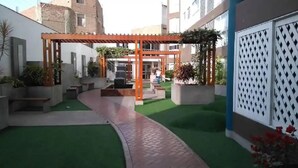Une cour dotée d’une pergola, d’un gazon synthétique vert et de plantes en pot.