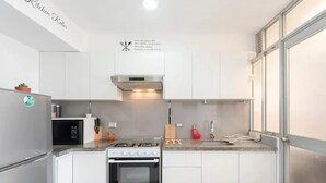 Une cuisine moderne avec des meubles blancs, une cuisinière en acier inoxydable, un four à micro-ondes et une cuisinière à gaz.