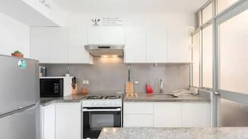 Una cocina moderna con armarios blancos, una estufa de acero inoxidable, un microondas y una cocina a gas.