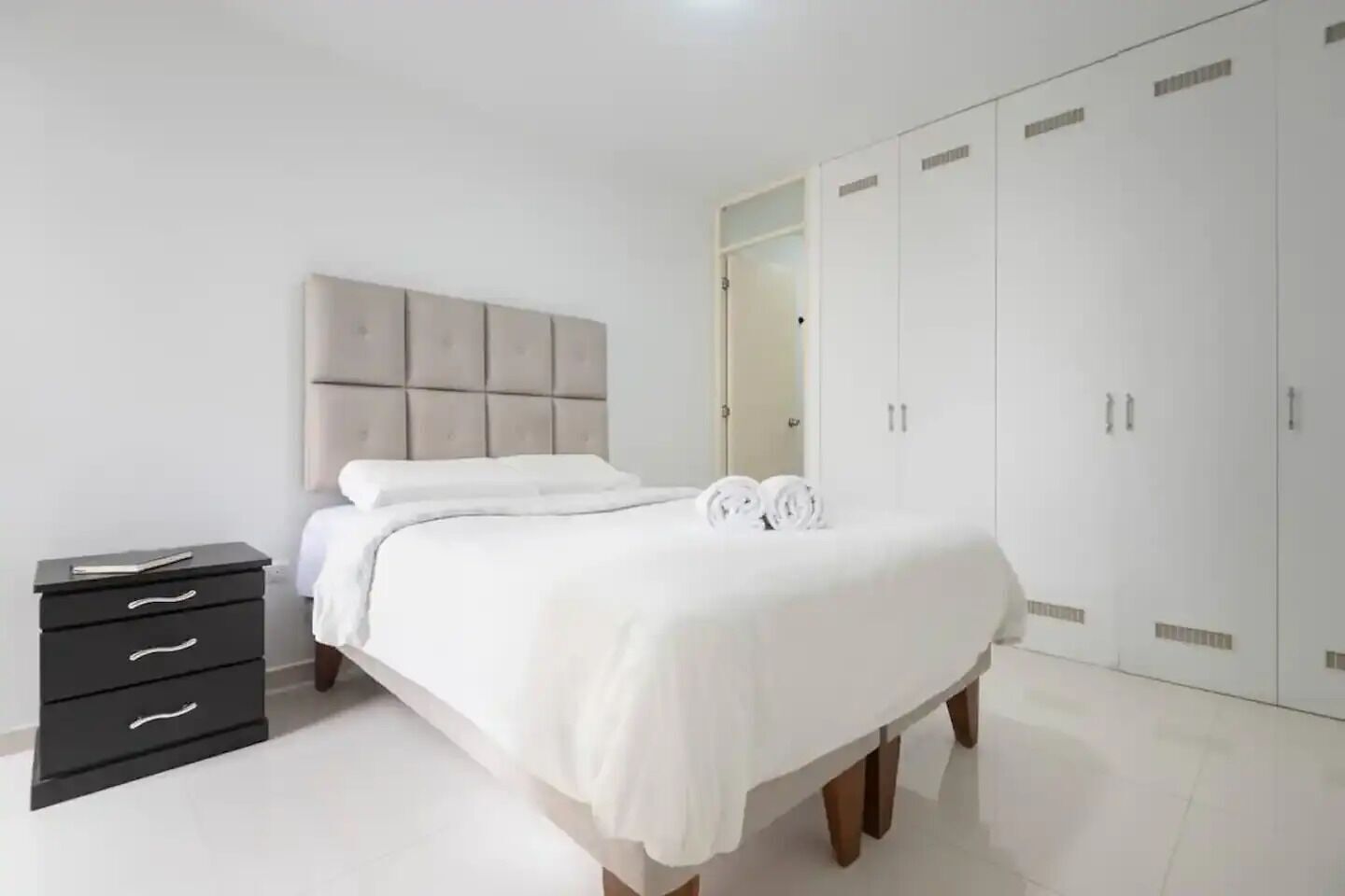 Un dormitorio con cama, mesita de noche, armario y espejo.