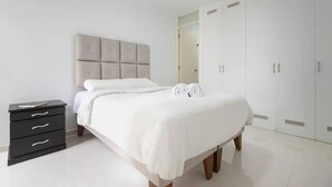 Une chambre à coucher comprenant un lit, une table de chevet, une armoire et un miroir.
