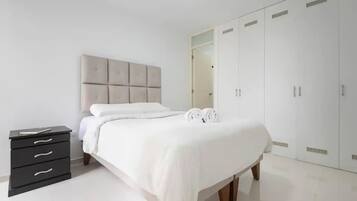 Un dormitorio con cama, mesita de noche, armario y espejo.