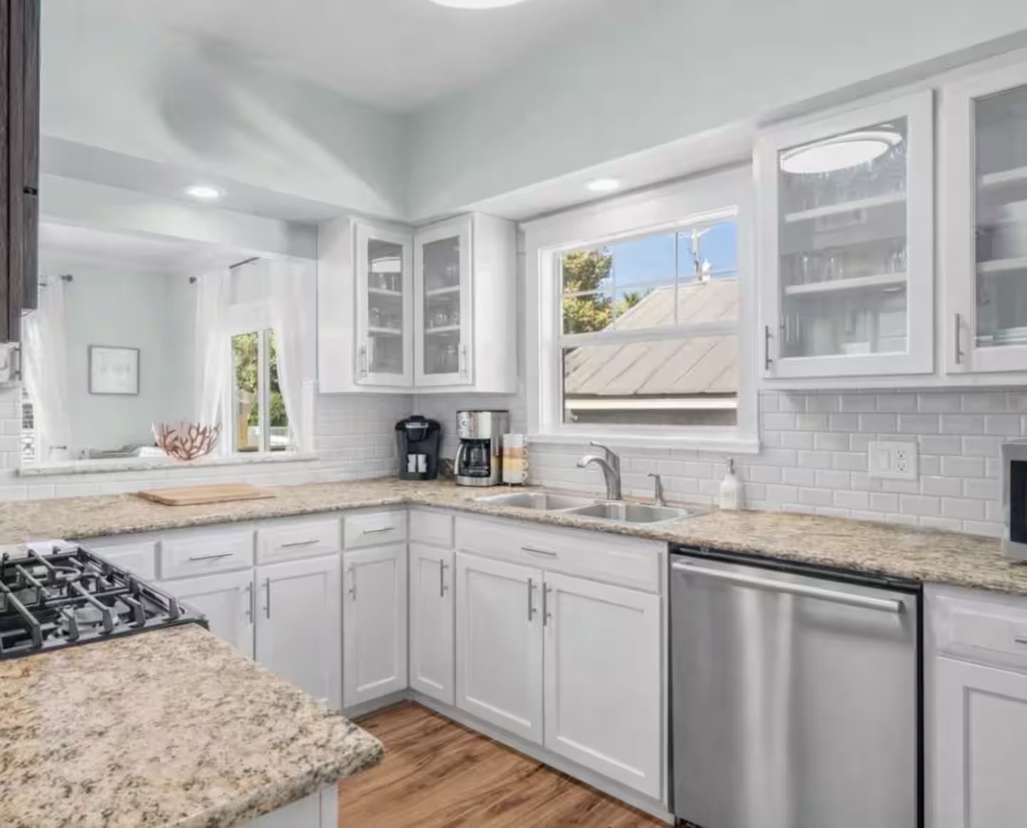 A modern kitchen with white cabinetry, a granite countertop, and a dishwasher.