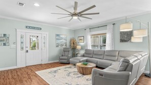Ein Wohnzimmer mit Ecksofa, Couchtisch und Deckenventilator.