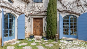 A building with a wooden door, blue shutters, and a stone pathway leading to the entrance. - Historic Villa 9 people, Private Pool, near Cannes (Grasse)