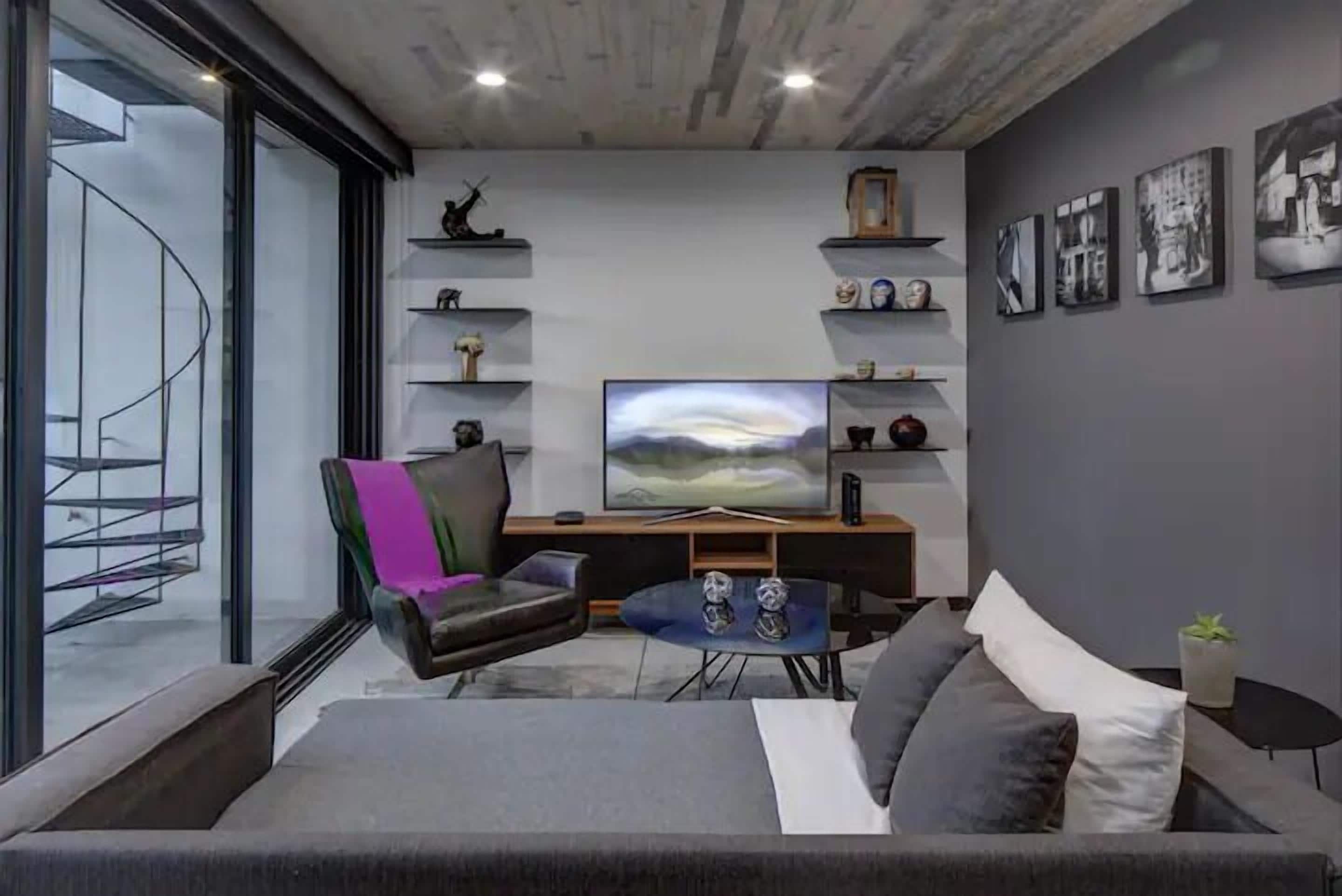 Una sala de estar moderna con una escalera curva, un televisor de pantalla plana y un sofá.