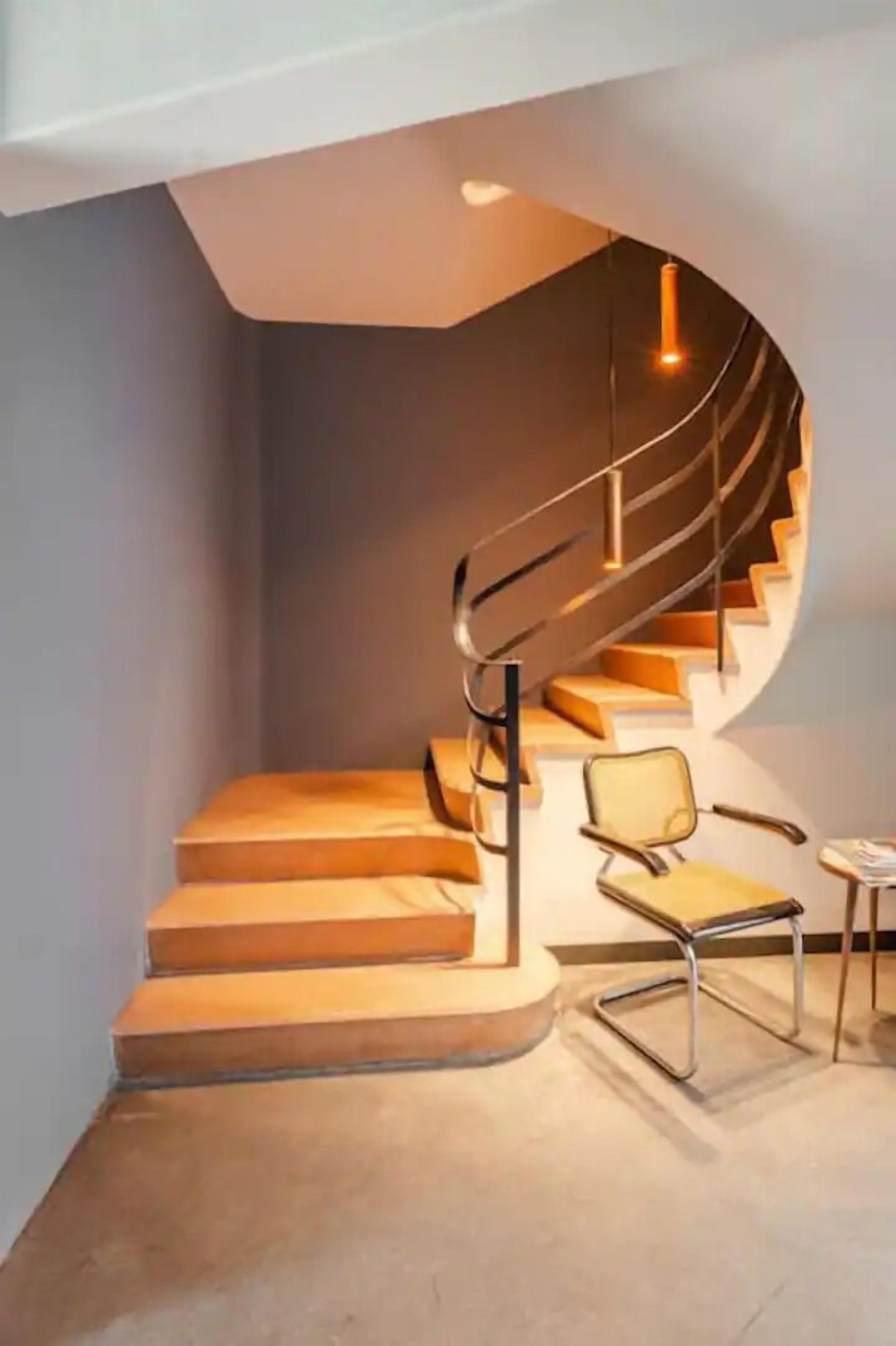 Un interior modern amb una escala corba, una taula rodona i una cadira.