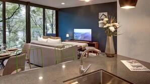 Una sala de estar moderna con sofá, televisor y comedor con pileta y sillas.