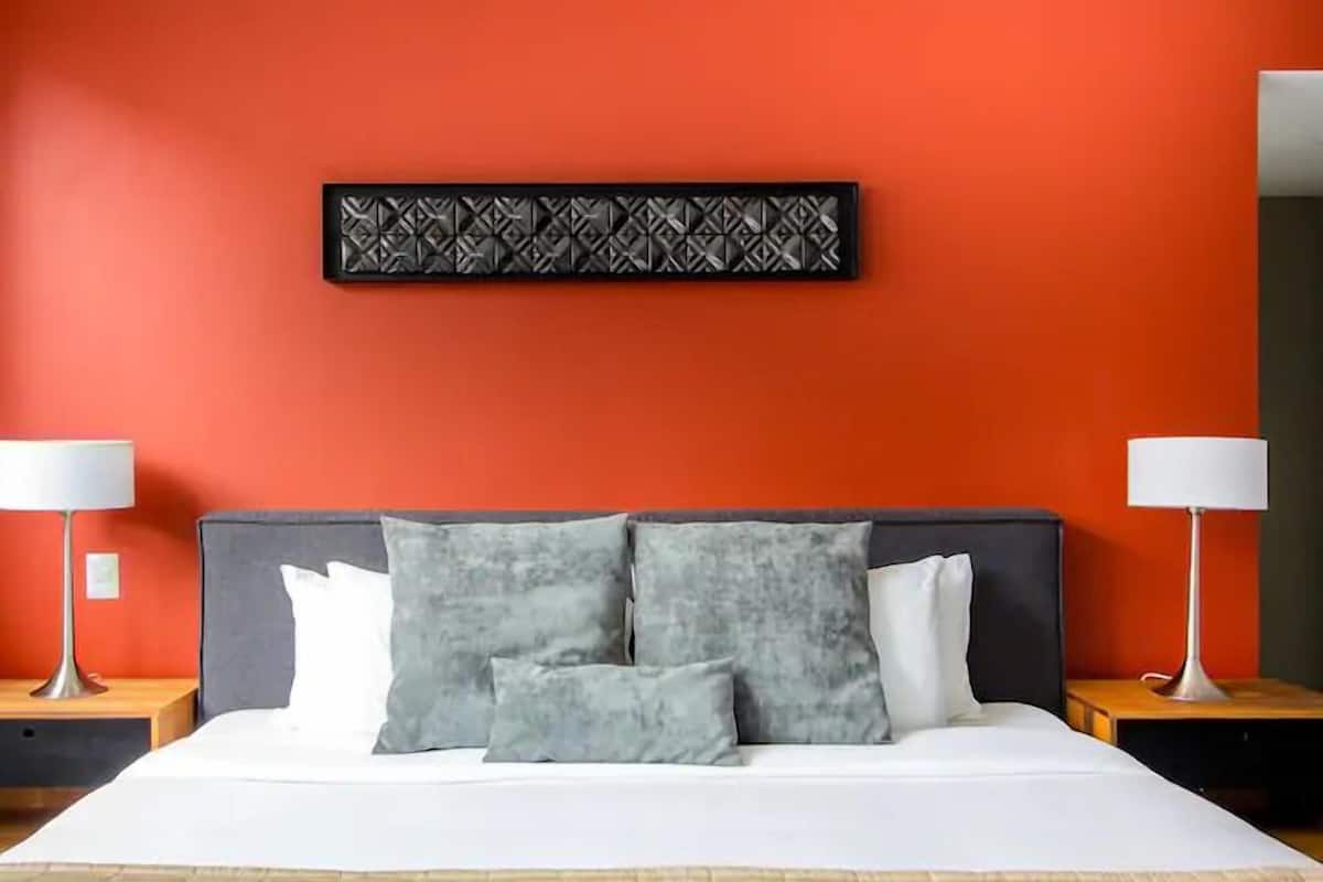 Une chambre d’hôtel avec un lit, deux tables de chevet et une œuvre d’art accrochée au mur.