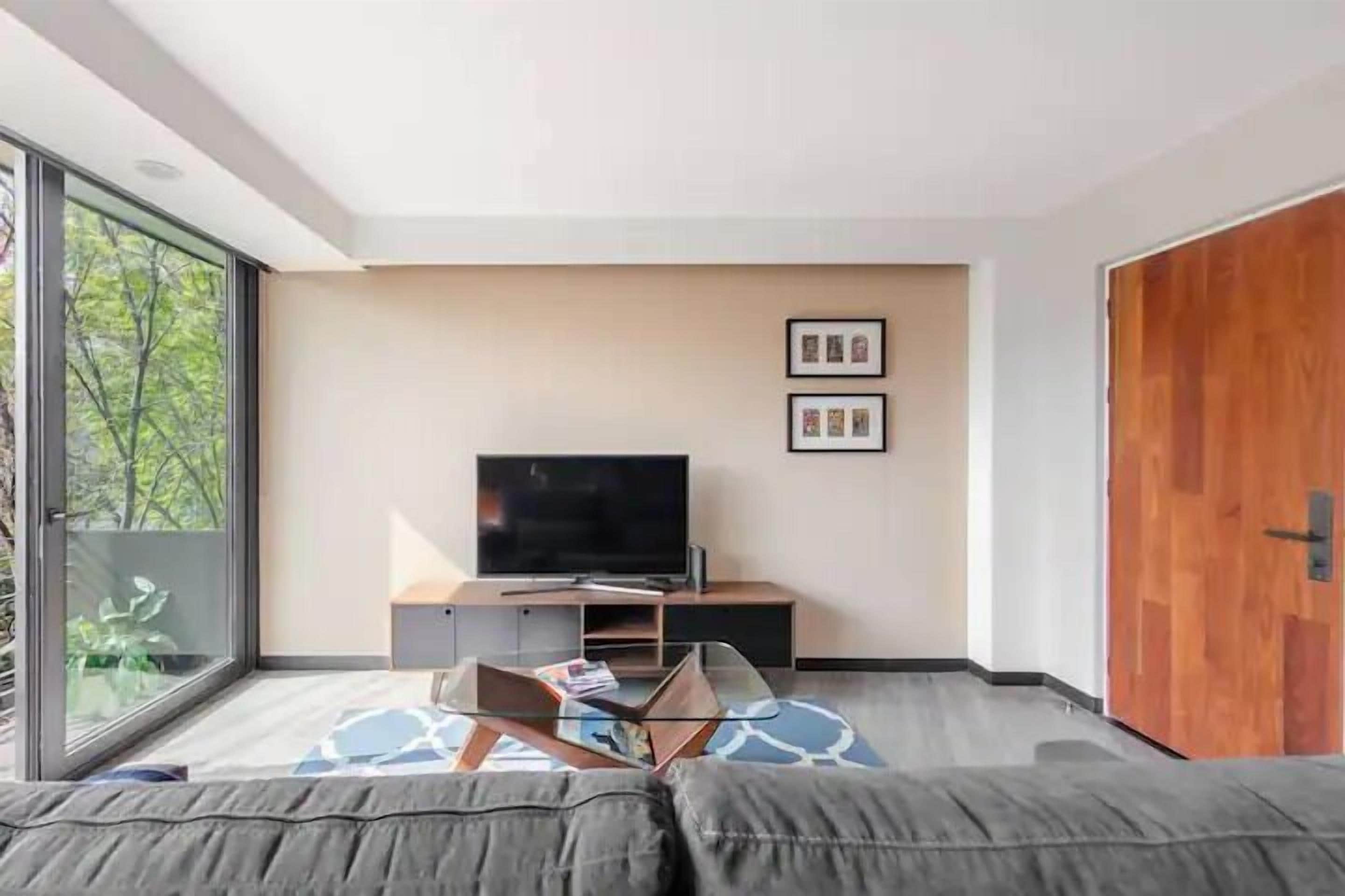 Un soggiorno moderno con una grande TV, un divano e un tavolino in vetro.