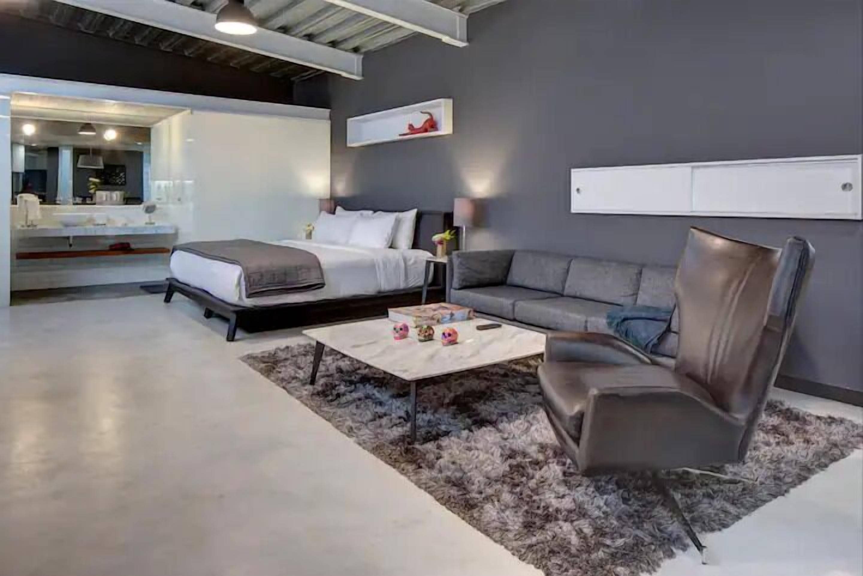 A modern bedroom with a bed, a sofa, a coffee table, and a mirror.