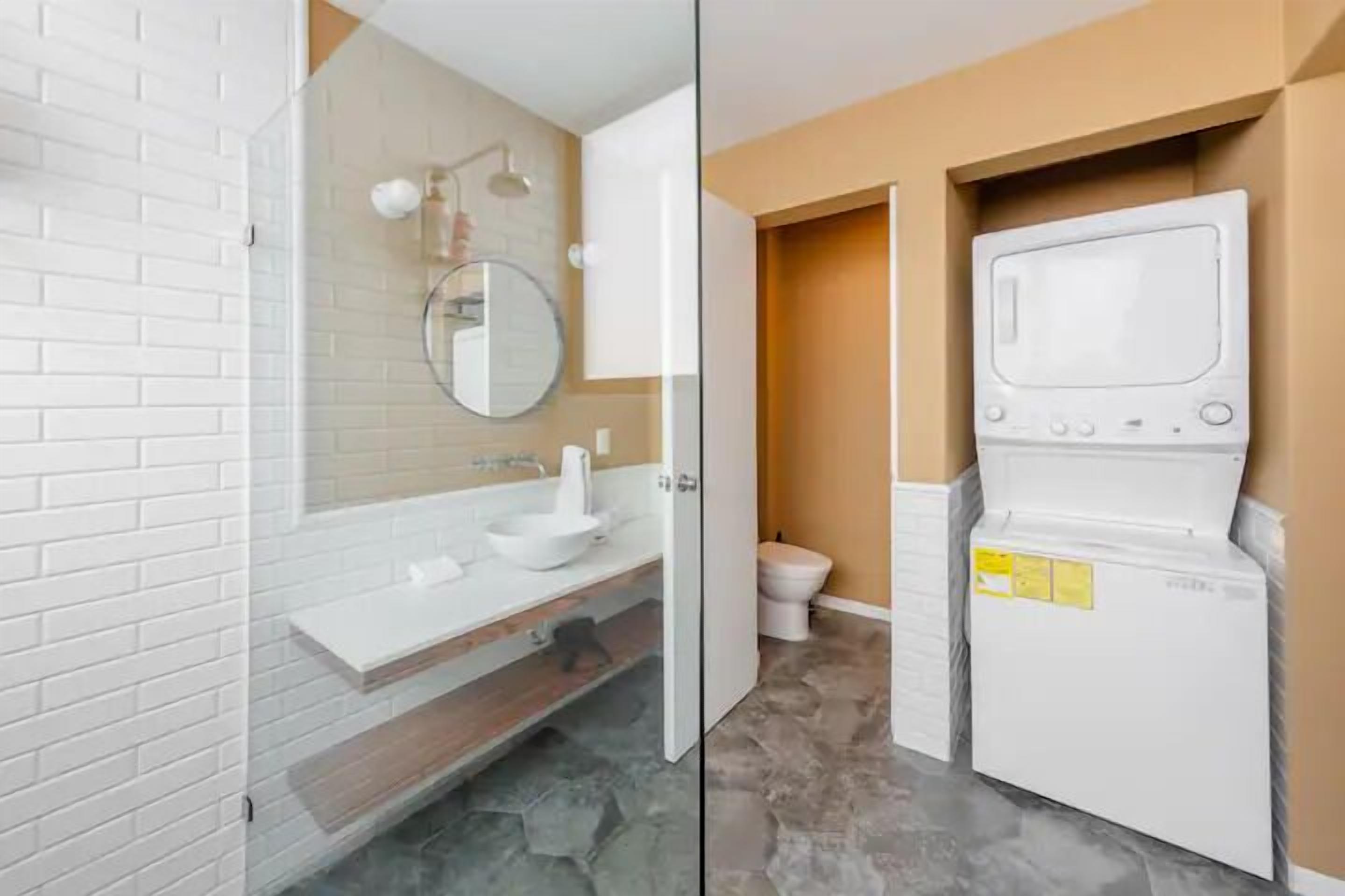A bathroom with a white sink, mirror, and toilet.
