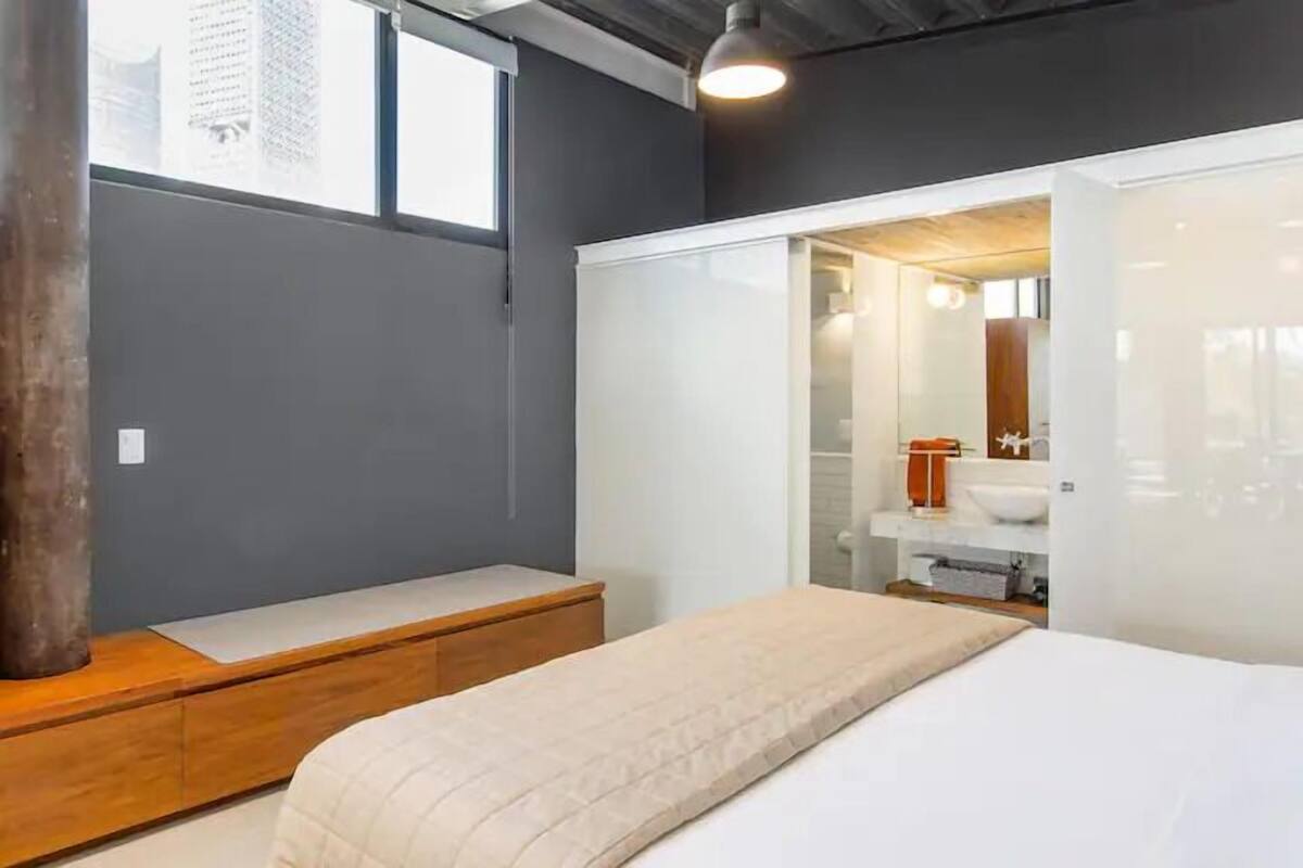 Une chambre à coucher moderne avec un lit, un banc et un dressing.