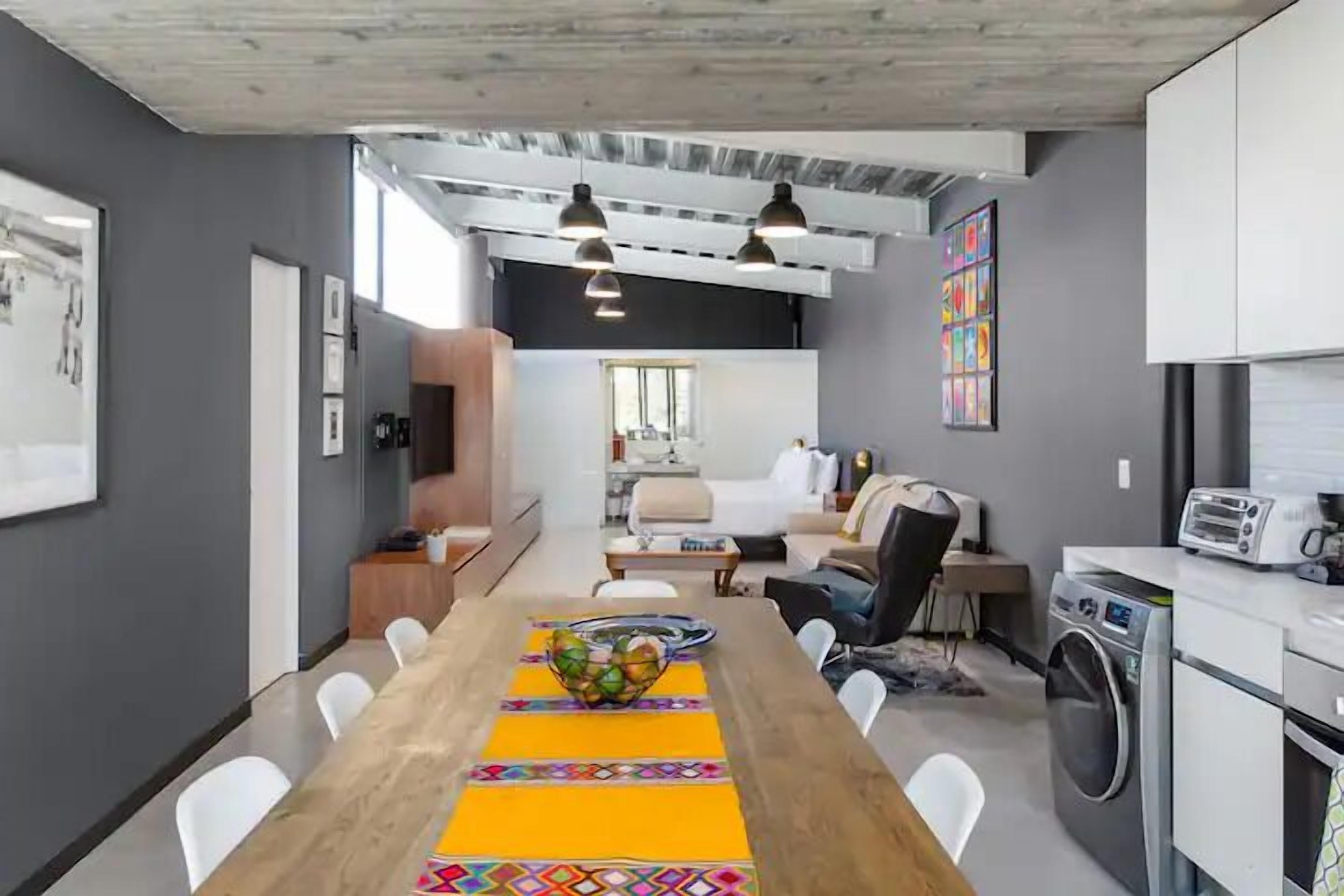 A modern kitchen with a dining area, a washing machine, and a large window.