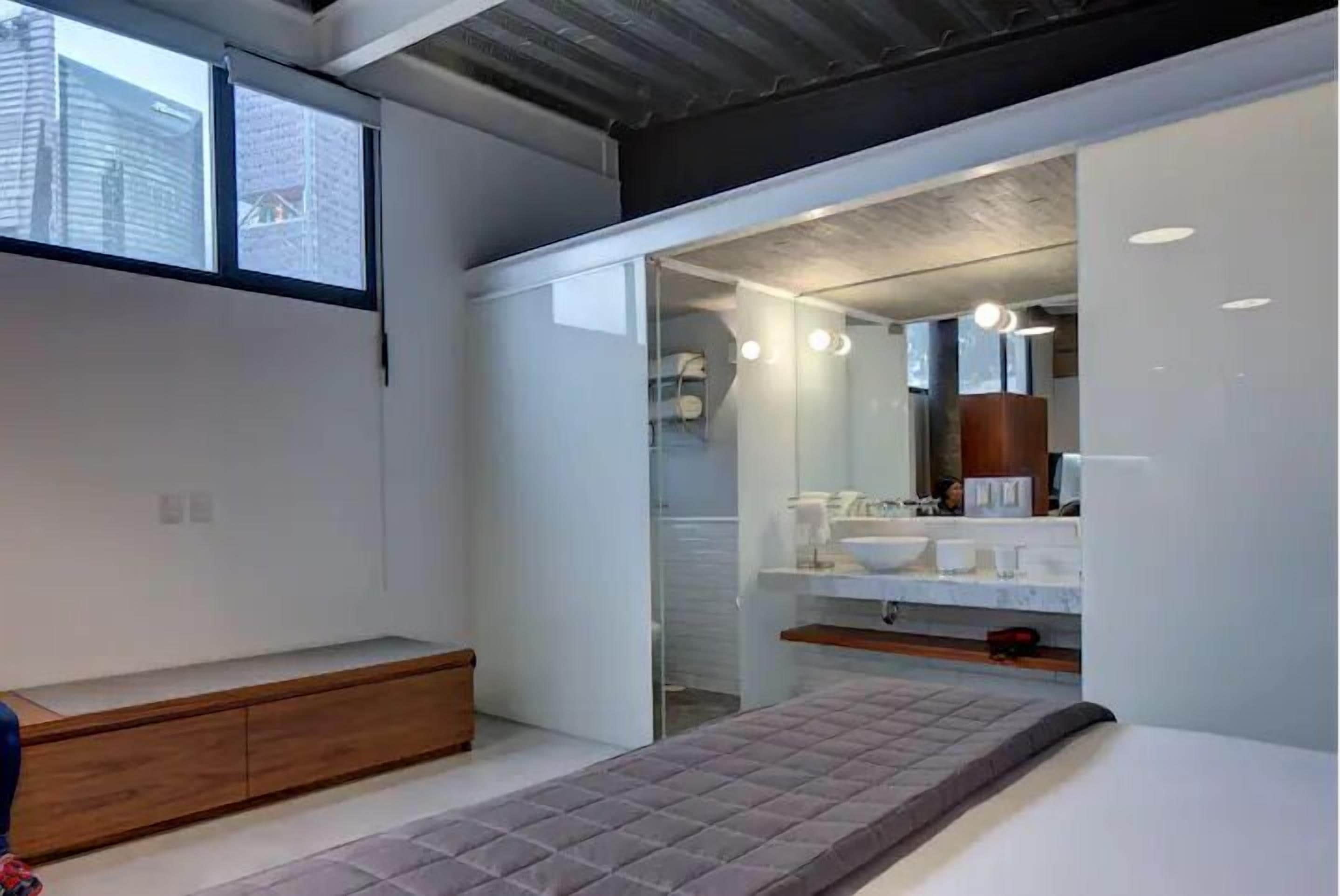 Un baño moderno con cabina de ducha de vidrio, un lavamanos blanco y un espejo sobre el lavamanos.