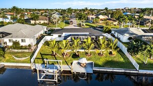 A residential area with houses, a dock, and a small boat. - Waterfront Bliss w/ Dock - Sunsets Over Del Prado (Cape Coral)