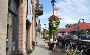 Vista de una calle con edificios de ladrillo, mesas al aire libre y una bandera canadiense.