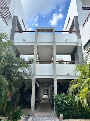 Un edificio moderno con un patio central, que presenta un diseño simétrico con pilares de concreto y balcones.