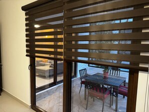 Una habitación con puerta de vidrio corredera que da a un patio exterior con mesa y sillas.