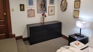 Una habitación con un aparador de color oscuro, un jarrón con flores y varias fotografías enmarcadas en la pared.