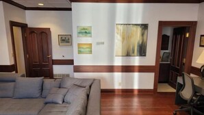 Una habitación con un amplio sofá seccional gris, suelo de madera y una pared decorada con tres obras de arte enmarcadas.