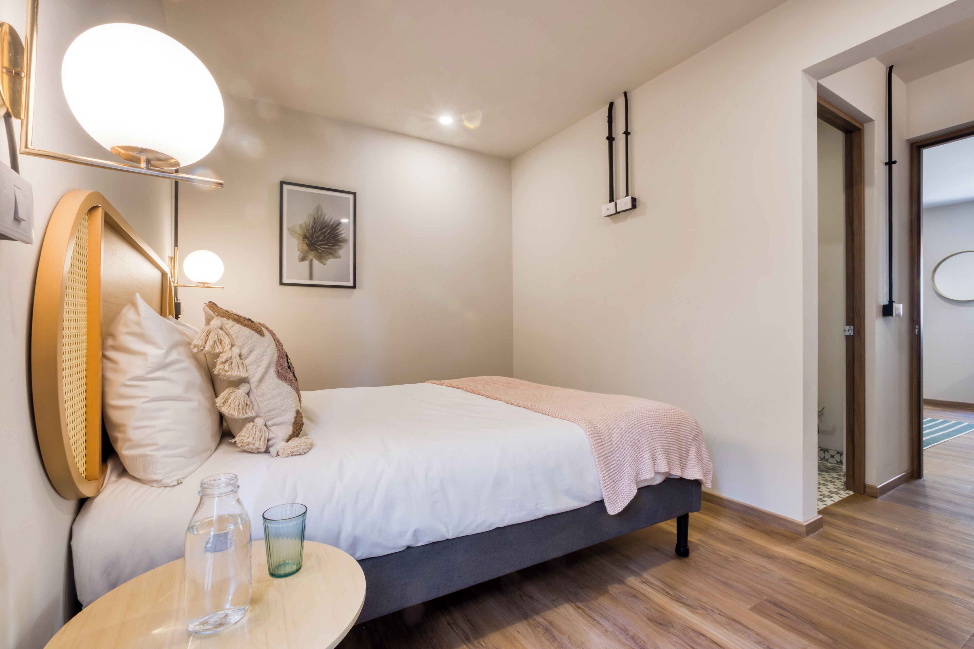 A modern bedroom with a bed, bedside table, and a mirror.