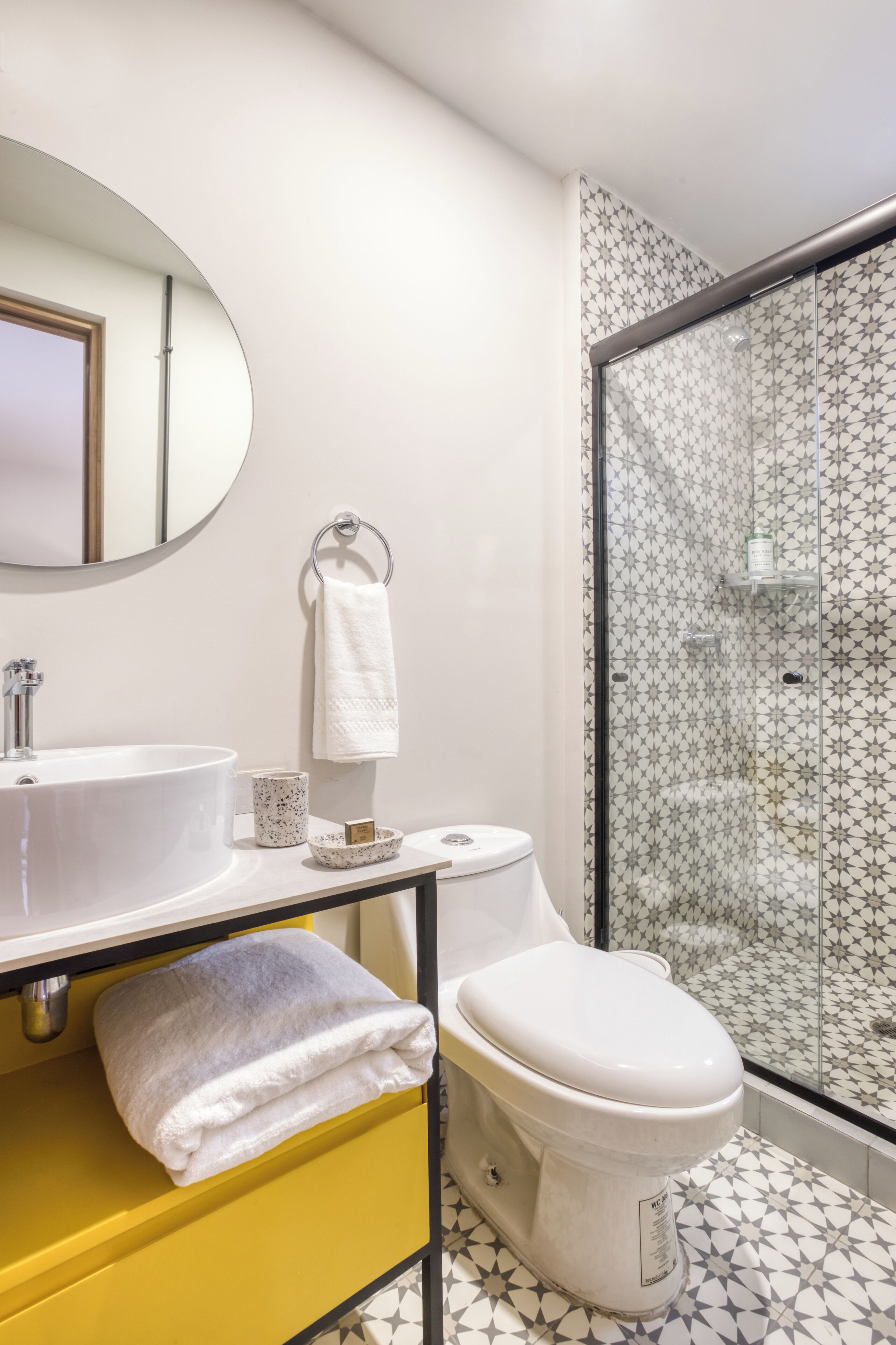 A bathroom with a white sink, yellow cabinet, white toilet, and a glass shower enclosure.