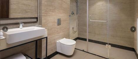A modern bathroom with a glass-enclosed shower, a white sink, and a toilet.