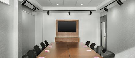 A conference room with a long table, chairs, a projector screen, and a door.