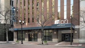 Un hotel con fachada moderna, amplias ventanas y un llamativo letrero de 'Alloft Hotels'.