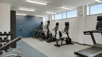 A gym with treadmills, elliptical machines, and dumbbells.