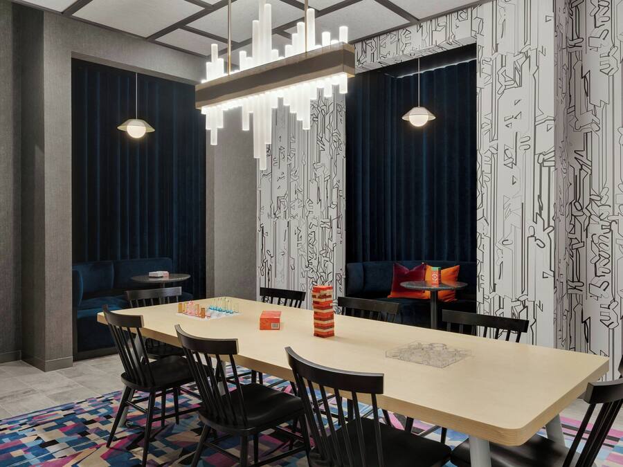 Un comedor moderno con una mesa larga, sillas negras y papel tapiz estampado.