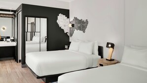 Una habitación de hotel moderna con dos camas, un espejo grande y una obra de arte original en la pared.