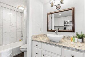 Ein modernes Badezimmer mit freistehender Badewanne, einem weißen Waschbecken und einem großen Spiegel.