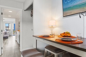 Eine moderne Küche mit Essbereich, ausgestattet mit einer Kücheninsel, orangefarbenen Untersetzern, einer Tischlampe und einer Obstschale.
