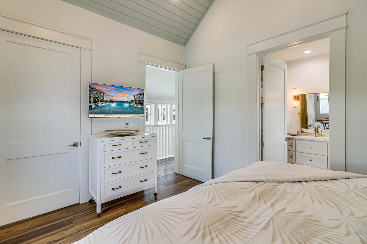 A bedroom with a bed, dresser, and a TV mounted on the wall.