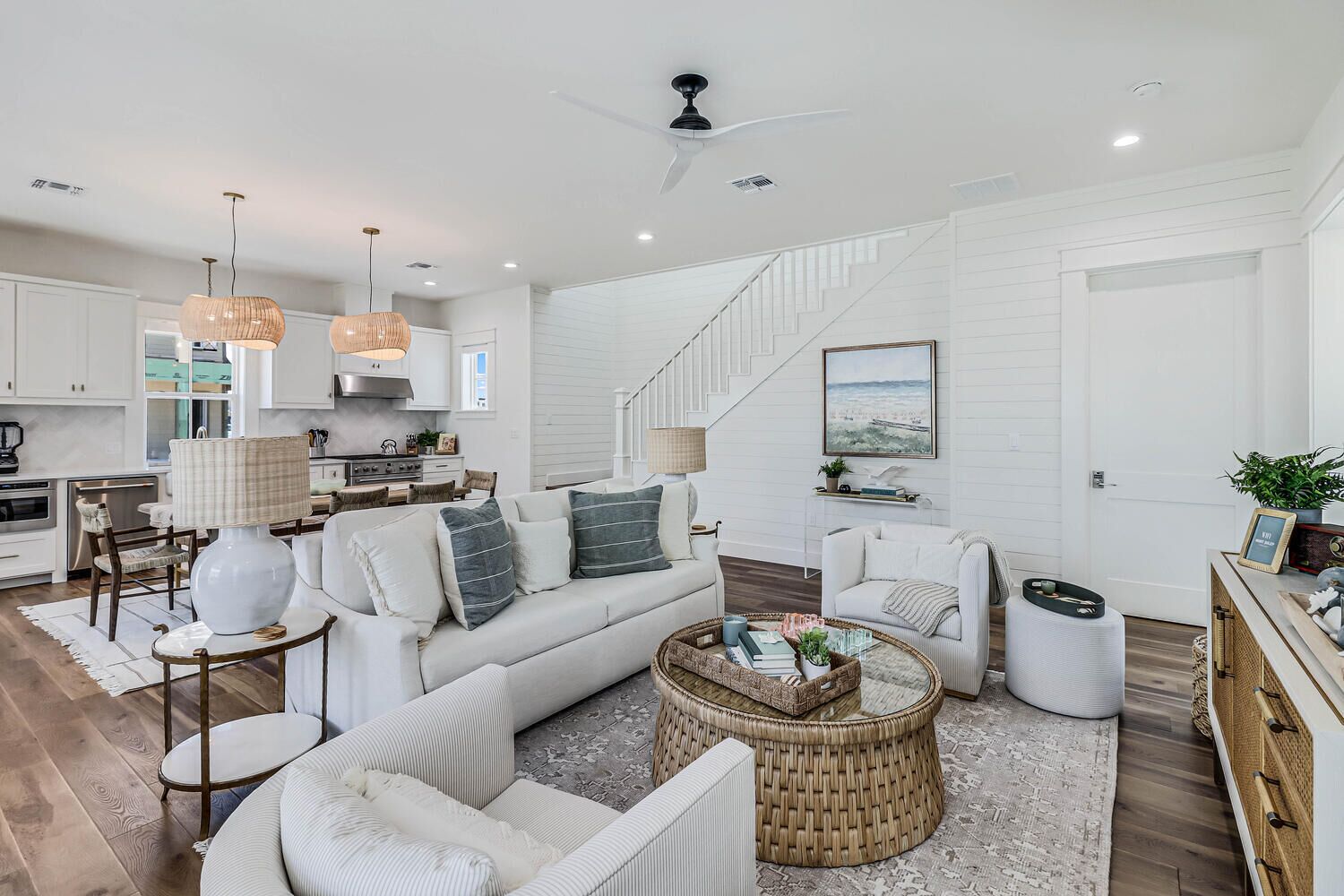 A spacious living room with a large sofa, a coffee table, and a dining area with a kitchen in the background.